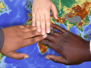 Drei H&auml;nde, die sich ber&uuml;hren &uuml;ber einer Weltkarte