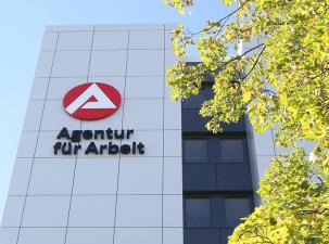Agentur f&uuml;r Arbeit - Au&szlig;enansicht mit Logo der AfA und einem Baum an einem sonnigen Tag