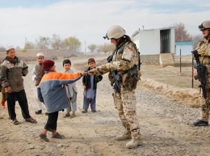 Soldat der Bundeswehr reicht kleinem Kind die Hand bei einem Auslandseinsatz in Syrien.