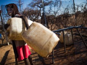 Ein afrikanisches Mädchen mit einem Wassereimer in der Hand