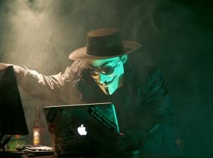 Ein Hacker mit Maske vor einem PC
