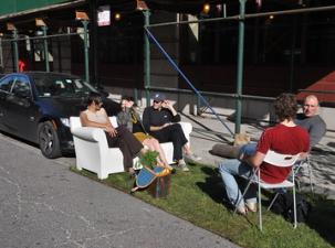 Eine Gruppe Aktivisten sitzen auf einem besetzten Parkplatz bei einem Parkingday