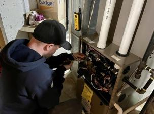 Ein Heizungstechniker bei der Arbeit an einem Heizkasten