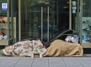 Ein Mann schl&auml;ft vor einem Gesch&auml;ft