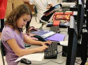 Ein M&auml;dchen an einem PC in einer Schule