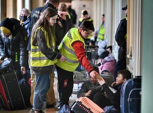 Zwei Freiwillige helfen einem Geflüchteten am Bahnhof