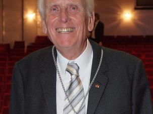 Ulrich Gottstein anl&auml;sslich der Verleihung der Paracelsus-Medaille beim 114. Deutschen &Auml;rztetag in Kiel - Ein &auml;lterer Mann mit wei&szlig;em Haar, l&auml;chelt in einem Anzug mit Krawatte und einer Medaille, vor einem Theater mit roten Sitzreihen.