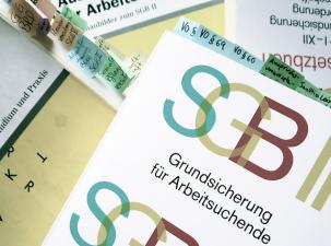 SGB II - Ein Stapel von Dokumenten, darunter ein Prospekt zur Grundsicherung f&uuml;r Arbeitsuchende und verschiedene Informationsbl&auml;tter.