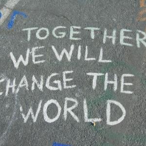 In weißer Schrift steht auf dem Asphalt: "Zusammen können wir alles ändern."