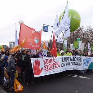 Eine Menschenmenge h&auml;lt Transparente und Fahnen bei einer Demonstration gegen Kohleverstromung, umgeben von gr&uuml;nen Ballons.