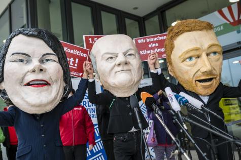 Eine Demo mit Masken der Gesichter von Scholz, Baerbock und Lindner