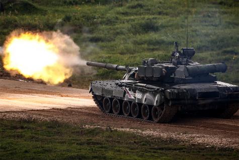 Ein schwarzer Armeepanzer f&auml;hrt einen Feldweg entlang und feuert auf die Stra&szlig;e.