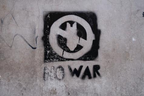 Man kann hier ein durchgestrichenes Bombensymbol erkennen, worunter in fetter Schrift "No War" steht.