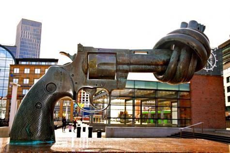Eine bronzerne Statue,  die einen Revolver zeigt, der am vorderen Ende zu einem Knoten gebunden ist. Die Statue steht im UN Hauptquartier in New York.