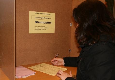 Eine Frau füllt ihre Wahlunterlagen in einer Wahlkabine aus