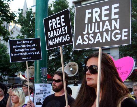 Viele Unterst&uuml;tzer von Julian Assange und Bradley Manning versammeln sich vor dem britischen Konsulat. Ein Mann und eine Frau im Vordergrund der anderen Demonstranten halten Schilder mit der Aufschrift "Free Julian Assange" und "Free Bradley Manning".