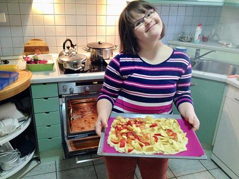 Eine Frau mit Down-Syndrom mit einem Backblech in der Hand
