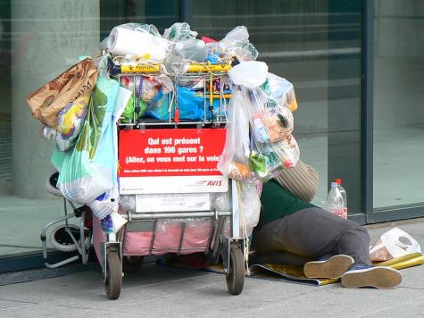 Ein obdachloser Mensch neben einem Wagen mit seinen Sachen