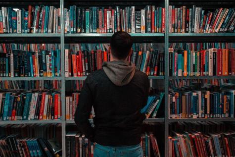 Ein Mann steht vor einem B&uuml;cherregal