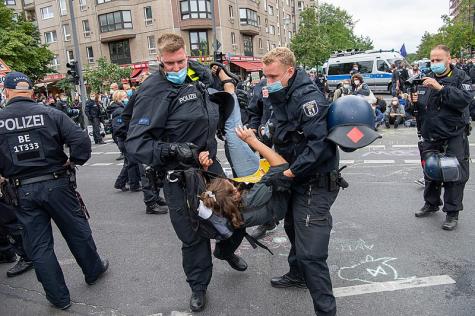 Zwei Polizisten tragen einen Demoteilnehmer weg