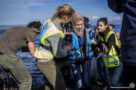 Eine Geflüchtete wird von zwei Helfern an Land geholfen aus einem Boot