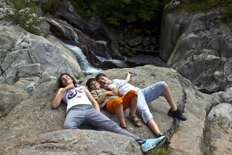 Drei Kinder liegen auf einer Felsplatte