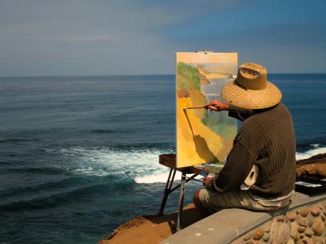 Ein Maler malt ein Bild vor einem Strandpanorama