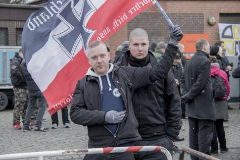 Zwei Neonazis auf einer Demo mit einer rechten Flagge