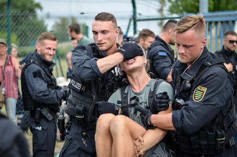 Zwei Polizisten tragen einen Demonstranten mit Gewalt weg