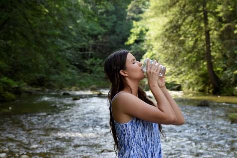 Frau am Fluss trinkt Wasser 