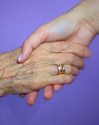 Ein junger Mensch reicht einer Seniorin die Hand