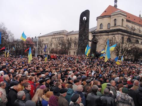 Regierungsfeindliche Demonstranten versammeln sich außerhalb von Kiew. Unter grauem Himmel halten Tausende von Demonstranten blaue und gelbe Ukraine-Fahnen.