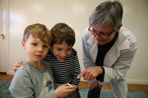Zwei Kinder und eine erwachsene Frau schauen auf ein Handy