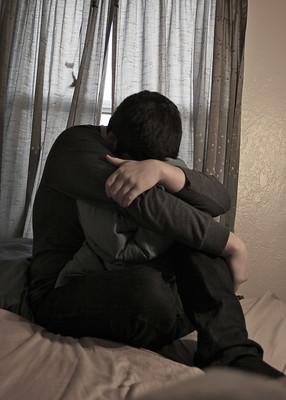 Ein Mensch sitzt auf dem Bett und sieht deprimiert aus