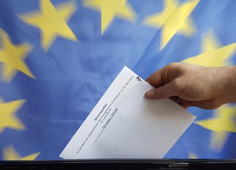 Eine Hand wirft einen Stimmzettel in eine Wahlurne