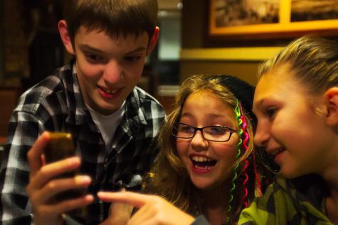 Drei Kinder, die mit einem Smartphone spielen