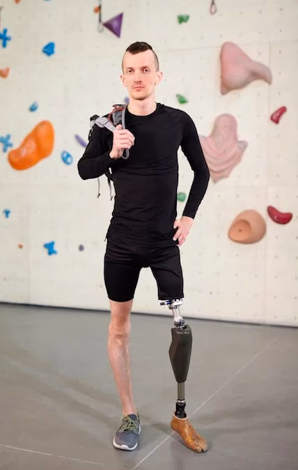 Mann mit einem Bein in Kletterhalle