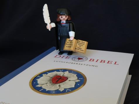 Hier siehst Du die Luther-Bibel mit wei&szlig;roter Rose und eine kleine Figur von Martin Luther