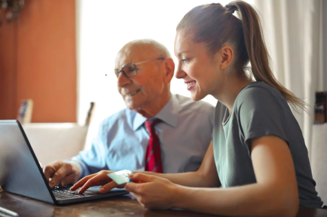 Junge Frau hilft altem Mann am Laptop