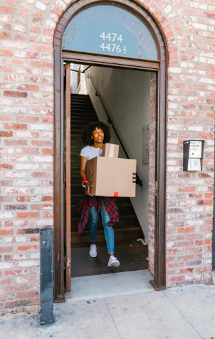 Mädchen trägt Kiste aus dem Haus