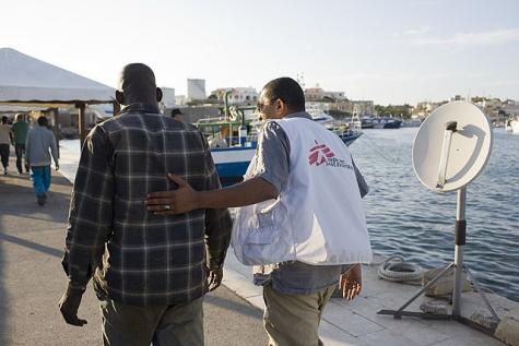 Ein NGO-Mitarbeiter begleitet einen Gefl&uuml;chteten an Land nach einer Boots&uuml;berfahrt