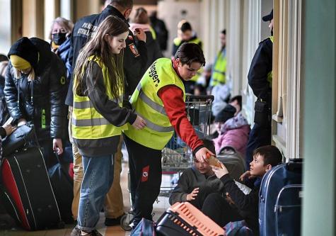 Zwei Freiwillige Helfer versorgen Gefl&uuml;chtete in einem Bahnhof