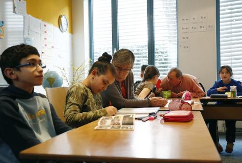 Ein Lerncafe der Caritas mit mehreren Kindern und Erwachsenen an einem Tisch