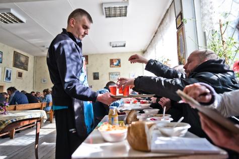 Ein Mann bedient mehrere Menschen in einer Suppenküche