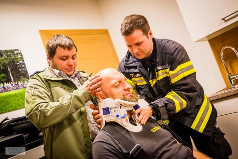 Zwei Freiwillige helfen einem Mann mit Halskrause