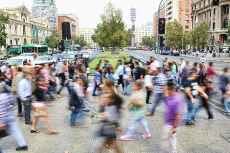 Eine Stra&szlig;e mit vielen Menschen, die sie &uuml;berqueren
