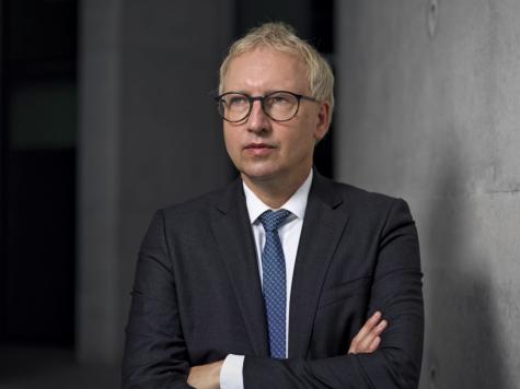 Prof. Johannes Varwick - Ein Mann mit blondem Haar und Brille steht in einem Anzug und schaut ernst in die Kamera, mit verschr&auml;nkten Armen.