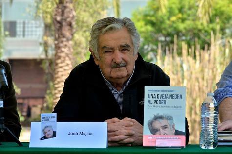 Jos&eacute; Mujica am Tisch mit verschr&auml;nkten H&auml;nden, vor ihm steht sein Buch bei einer Lesung zur Neuerscheinung.