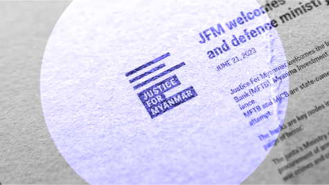 Ein Spotlicht f&auml;llt auf ein bedrucktes Papier mit dem Logo von Justice for Myanmar in der Mitte.