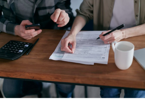 Zwei Menschen am Tisch mit Rechnungen